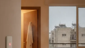 מתג דוד על קיר המסדרון בבוקר חורפי מעונן, ובחלון נראים קולטי שמש על גג סמוך
